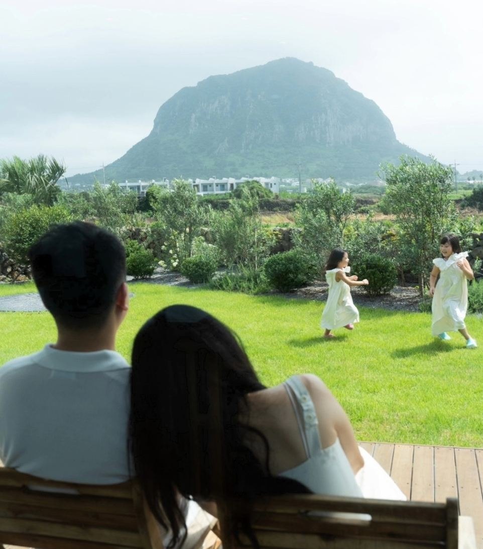 잔디 정원에서 뛰노는 아이들을 바라보는 부모의 뒷모습, 뒤로 산방산